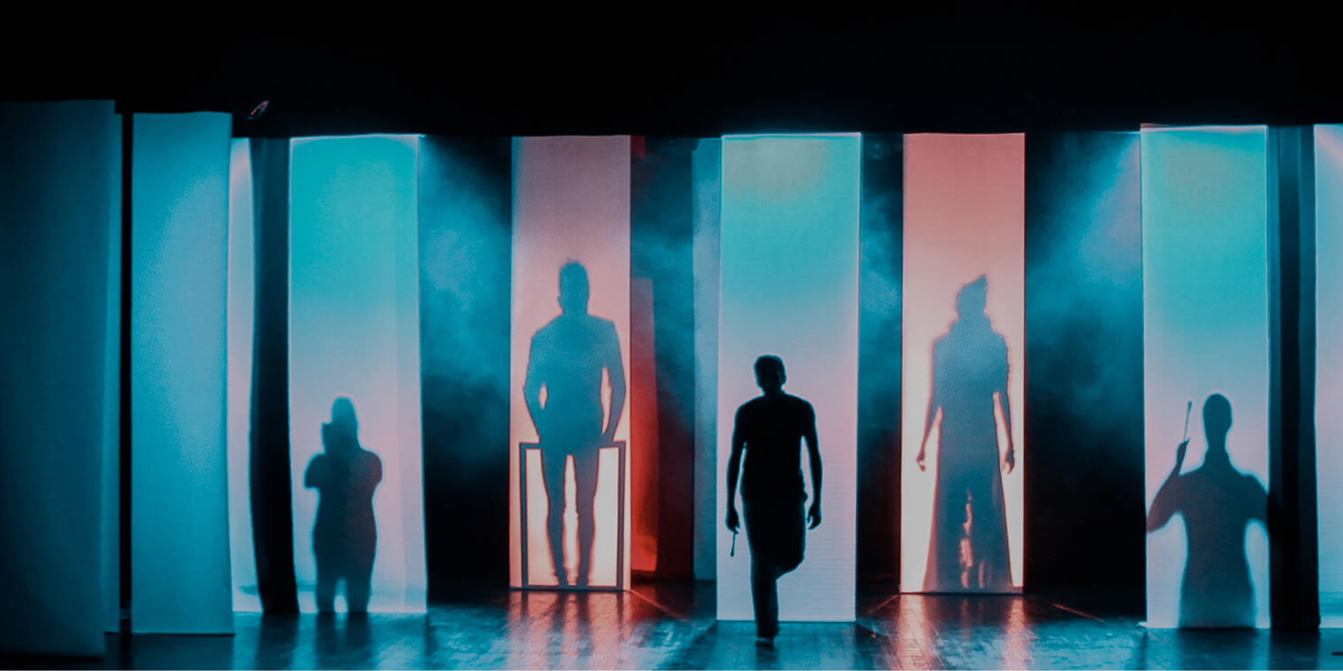 Shadows of actors on a stage behind red and blue screens